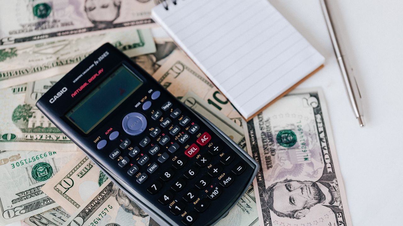 Coach bepaalt prijs voor online cursus met calculator en laptop